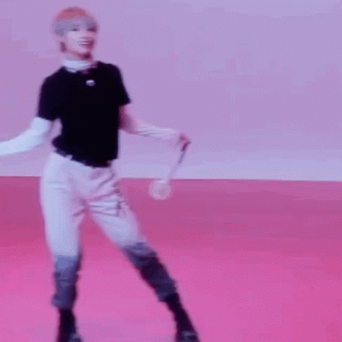 A Young Man Is Standing On A Pink Floor Holding A Microphone . GIF