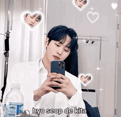 A Young Man Is Taking A Selfie In Front Of A Mirror With His Phone . GIF