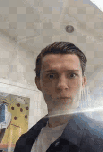 A Young Man Is Taking A Selfie With His Face Reflected In A Mirror . GIF