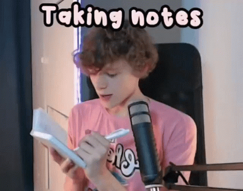A Young Man Is Taking Notes In Front Of A Microphone While Sitting In Front Of A Book . GIF