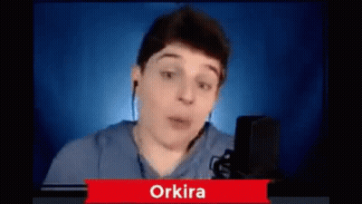 A Young Man Is Talking Into A Microphone While Wearing Ear Buds . GIF