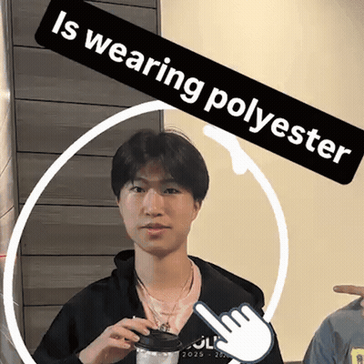 A Young Man Is Wearing A Black Jacket And Holding A Cup Of Coffee Under A Banner That Says " Is Wearing Polyester " GIF