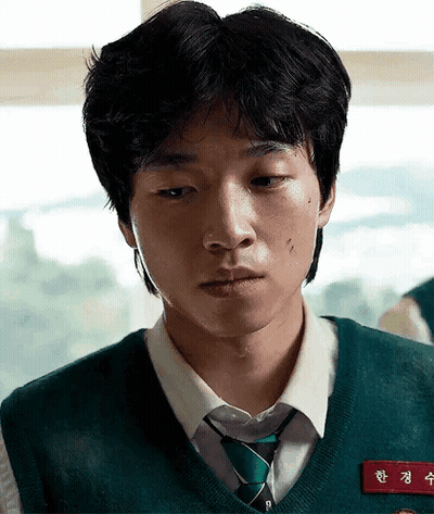 A Young Man Is Wearing A Green Vest And Tie And Has A Name Tag On His Chest . GIF