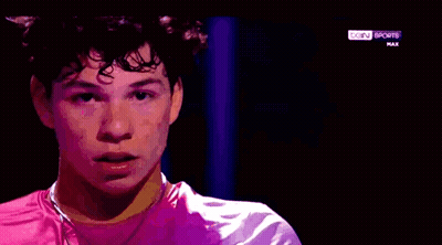 A Young Man Is Wearing A Pink Shirt And A Purple Jacket On A Sports Channel . GIF