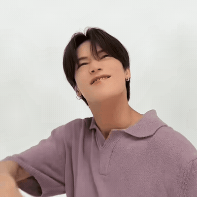 A Young Man Is Wearing A Purple Polo Shirt And Looking Up At The Camera . GIF