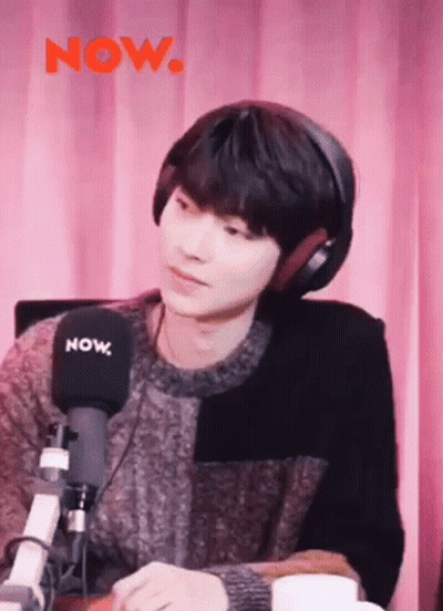 A Young Man Is Wearing Headphones And Sitting In Front Of A Microphone . GIF