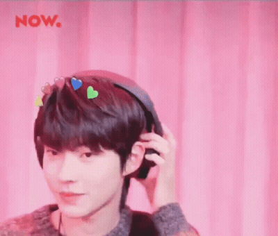 A Young Man Is Wearing Headphones With Hearts On His Head . GIF
