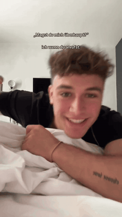 A Young Man Laying On A Bed With A Tattoo On His Arm GIF
