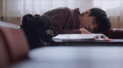 A Young Man Laying On A Couch With His Head On A Book . GIF