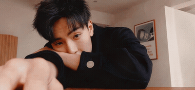 A Young Man Rests His Head On His Arm In Front Of A Framed Picture That Says Oa GIF