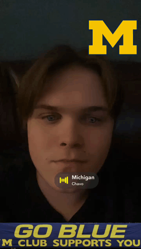 A Young Man 'S Face Is Behind A Banner That Says " Go Blue M Club Supports You " GIF