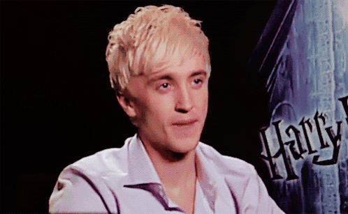 A Young Man Sitting In Front Of A Harry Potter Sign GIF