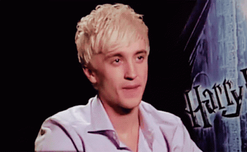 A Young Man Sitting In Front Of A Harry Potter Sign GIF
