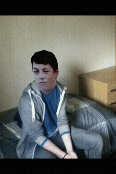 A Young Man Sitting On A Bed With A Picture Of His Face On His Chest GIF