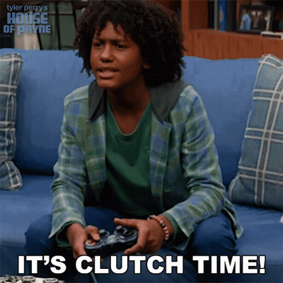 A Young Man Sitting On A Couch Playing A Video Game With The Words It 'S Clutch Time Below Him GIF