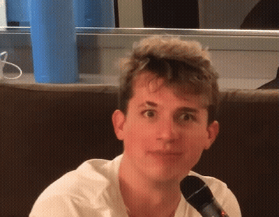 A Young Man Sitting On A Couch With A Microphone GIF
