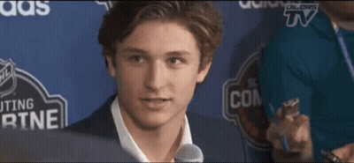 a young man speaking into a microphone in front of a sign that says ' dillors tv ' on it