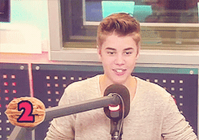 A Young Man Stands In Front Of A Microphone With The Number 2 On A Nut GIF