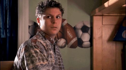 A Young Man Stands In Front Of A Wall With Footballs And Soccer Balls Painted On It GIF