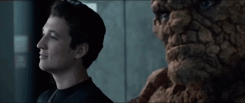 A Young Man Stands Next To A Statue Of A Man GIF