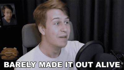 A Young Man Talking Into A Microphone With The Words Barely Made It Out Alive Above Him GIF