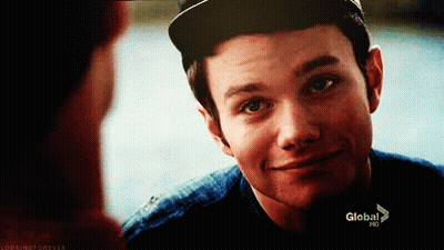 A Young Man Wearing A Baseball Cap Is Smiling And Looking At Another Man . GIF