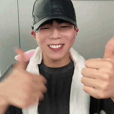 A Young Man Wearing A Black Hat Is Giving A Thumbs Up Sign GIF