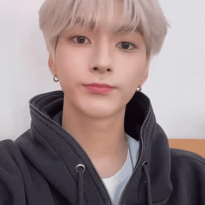 A Young Man Wearing A Black Hoodie And Earrings Is Looking At The Camera . GIF