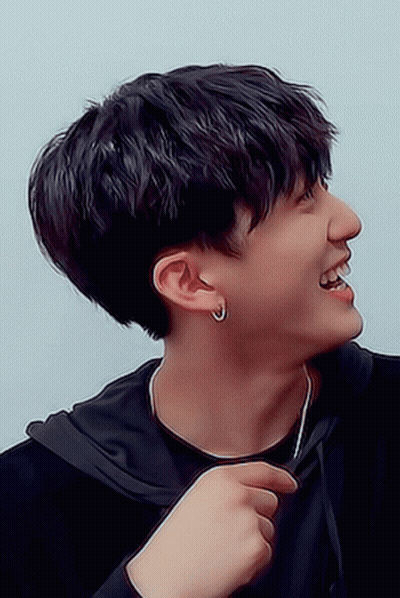 A Young Man Wearing A Black Hoodie And Earrings Smiles GIF