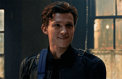 A Young Man Wearing A Black Jacket And A Blue Backpack Is Smiling GIF