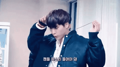 A Young Man Wearing A Black Jacket And A White Shirt Is Holding A String Around His Neck . GIF