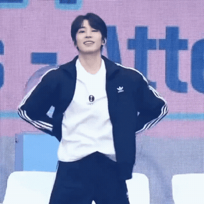 A Young Man Wearing A Black Jacket And A White Shirt Is Standing On A Stage . GIF