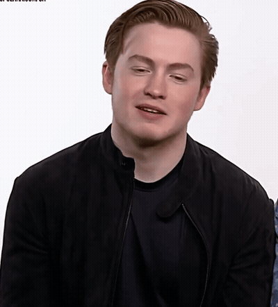 A Young Man Wearing A Black Jacket And Black Shirt Looks At The Camera GIF