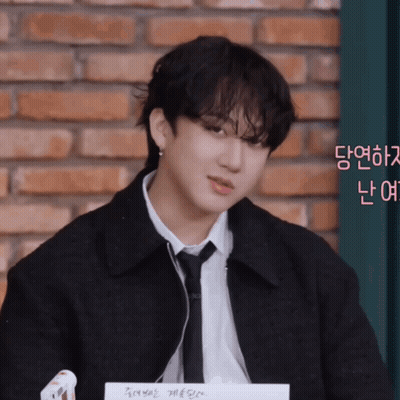 A Young Man Wearing A Black Jacket And Tie Looks At The Camera GIF
