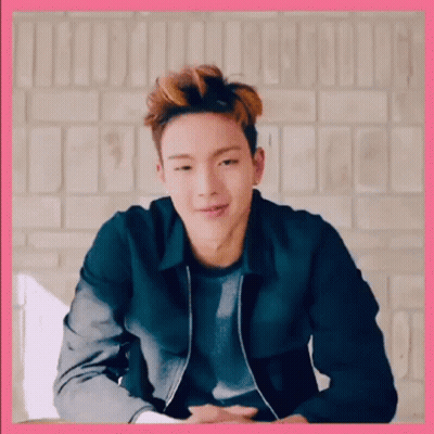 A Young Man Wearing A Black Jacket Is Sitting In Front Of A Brick Wall . GIF