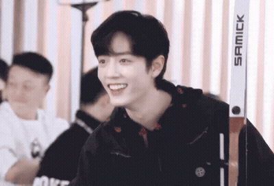 A Young Man Wearing A Black Jacket Is Smiling While Standing Next To A Pair Of Skis . GIF