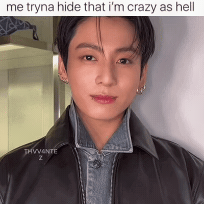 A Young Man Wearing A Black Leather Jacket And A Denim Jacket Is Standing In Front Of A Wall . GIF