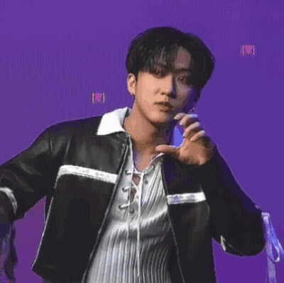 A Young Man Wearing A Black Leather Jacket And A White Shirt Is Dancing On A Purple Background . GIF