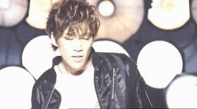 A Young Man Wearing A Black Leather Jacket Is Standing In Front Of A Wall Of Lights . GIF