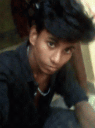 A Young Man Wearing A Black Shirt And A Black Hat Looks At The Camera GIF
