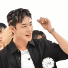 A Young Man Wearing A Black Shirt And A Name Tag Is Raising His Fist . GIF