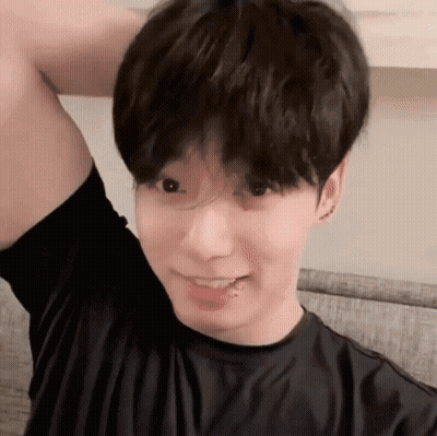 A Young Man Wearing A Black Shirt Is Smiling With His Arm Up GIF