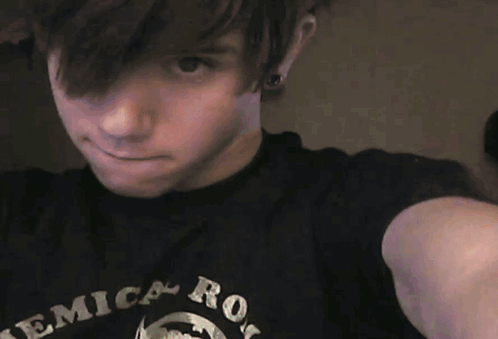 A Young Man Wearing A Black Shirt That Says ' Erica Rock ' On It GIF