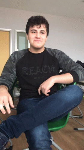 A Young Man Wearing A Black Shirt That Says Reach GIF