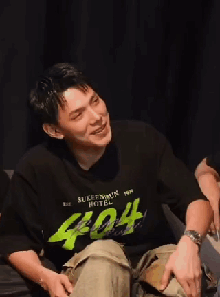 A Young Man Wearing A Black Shirt With The Number 404 On It Is Sitting On A Couch . GIF