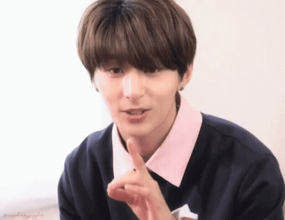 A Young Man Wearing A Black Sweater And A Pink Collar Holds His Finger To His Lips GIF