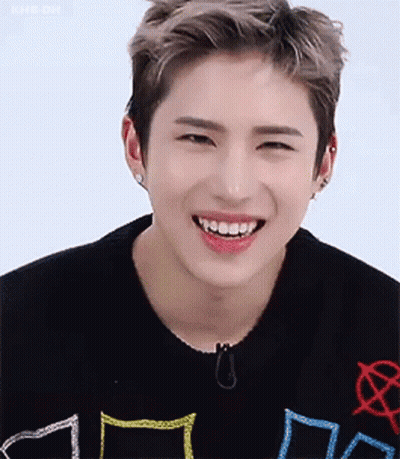 A Young Man Wearing A Black Sweater Is Smiling With His Teeth Showing . GIF