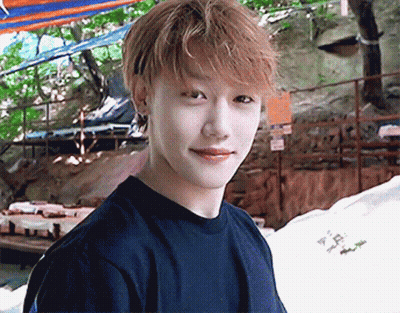 A Young Man Wearing A Black T-Shirt Is Smiling And Looking At The Camera GIF