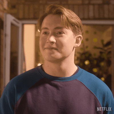 A Young Man Wearing A Blue And Purple Sweater With A Netflix Logo On The Back . GIF