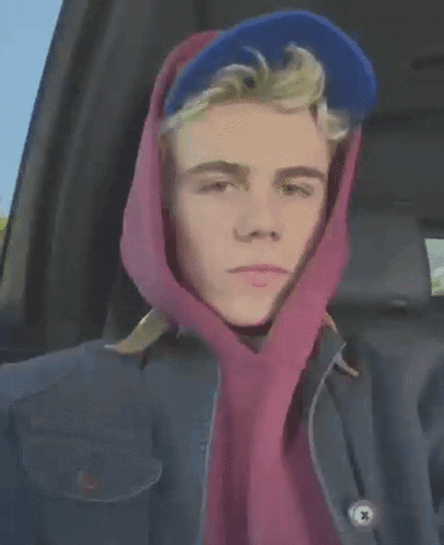 A Young Man Wearing A Blue Hat And A Pink Scarf Around His Head GIF
